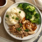 Juicy crockpot chicken breasts cooked in a slow cooker with honey garlic sauce, garnished with sesame seeds and green onions