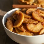 Homemade apple pie filling recipe with cinnamon spiced apple slices in glossy sauce in white bowl