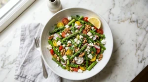 Asparagus salad recipe white bowl blanched asparagus feta cherry tomatoes walnuts lemon dressing overhead